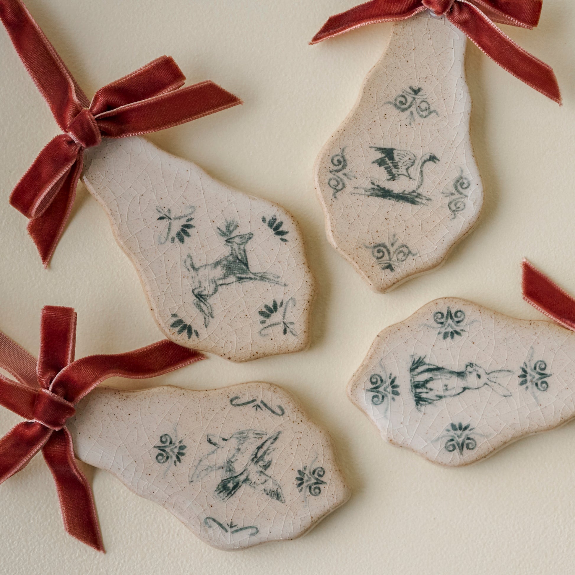 Decorative ceramic pieces with animal illustrations and red ribbons on a light background