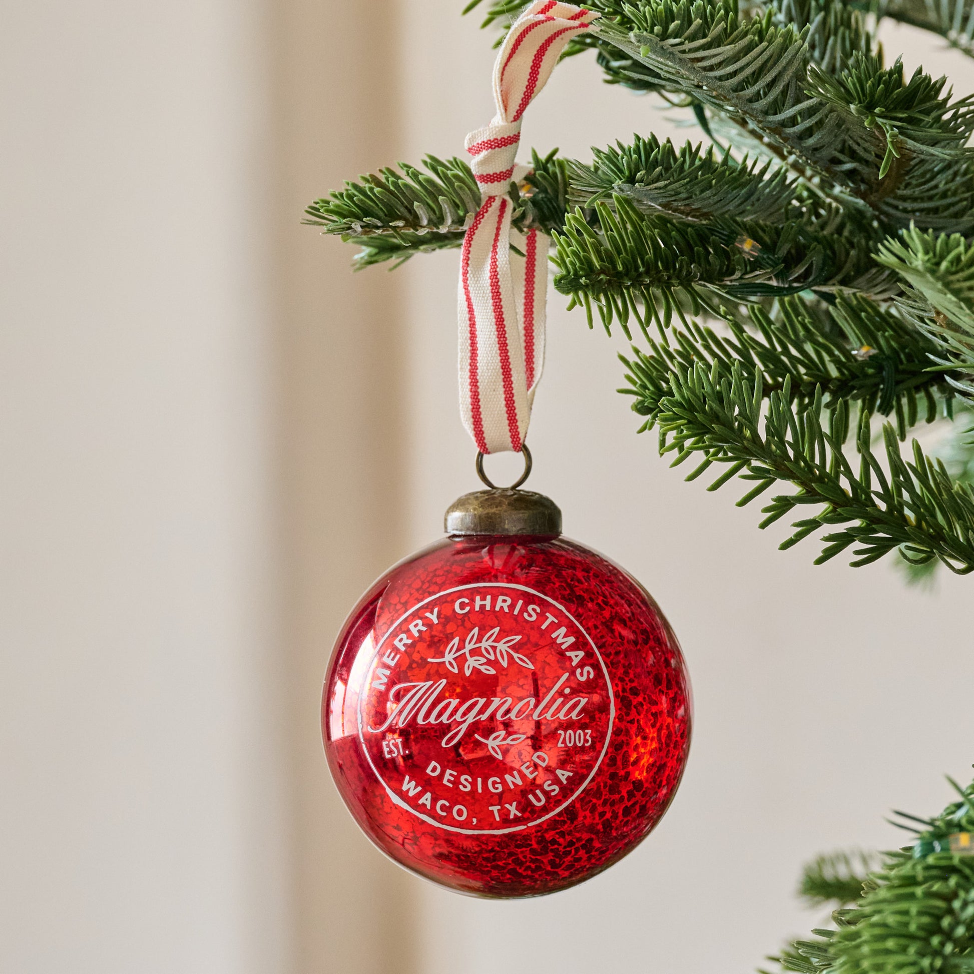 Magnolia Mercury Glass Ornament showhn hung from branch