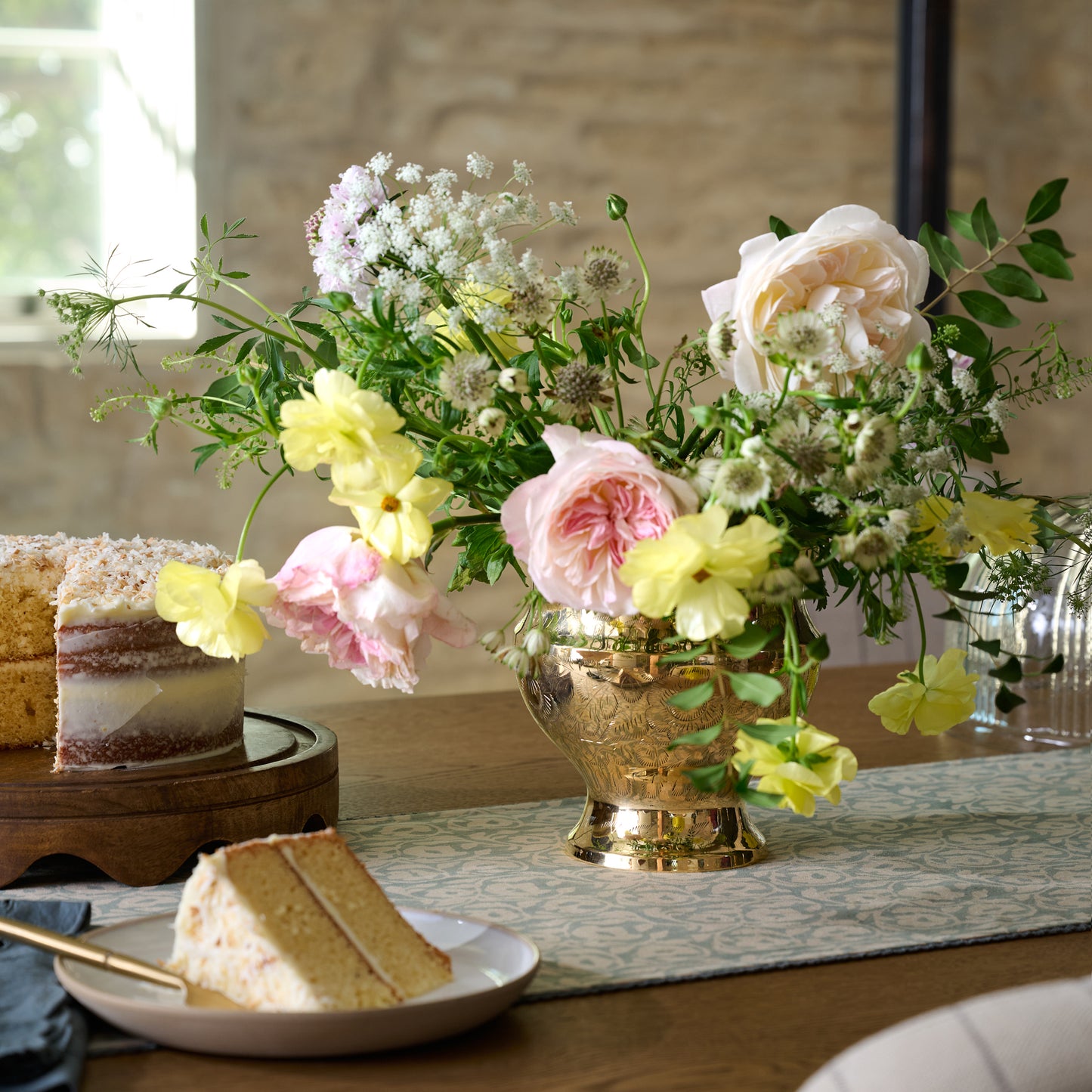 Delphine Antique Solid Brass Vase with Flower Frog on tabletop with bouquet of flowers 