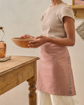 Magnolia Est. Jacquard Tea Towel Apron - Pink on a person