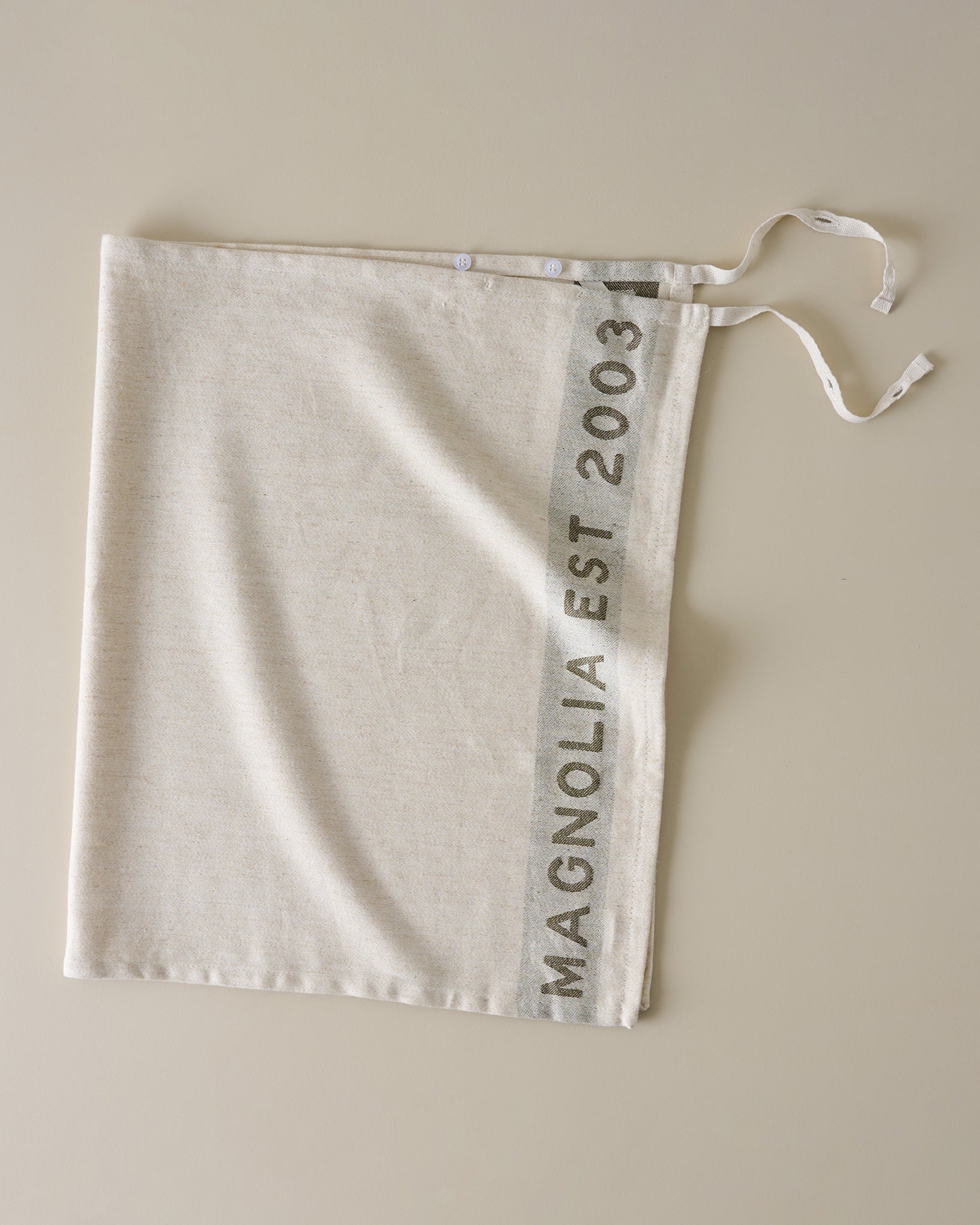 Magnolia Est. Jacquard Tea Towel - Green placed as an apron