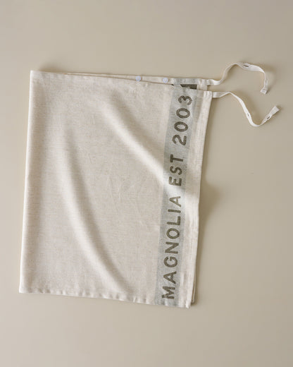 Magnolia Est. Jacquard Tea Towel - Green placed as an apron
