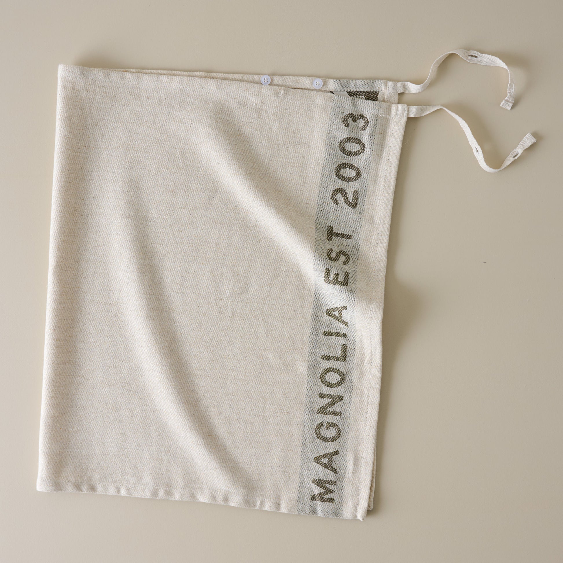 Magnolia Est. Jacquard Tea Towel - Green placed as an apron