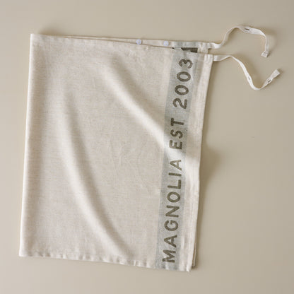 Magnolia Est. Jacquard Tea Towel - Green placed as an apron