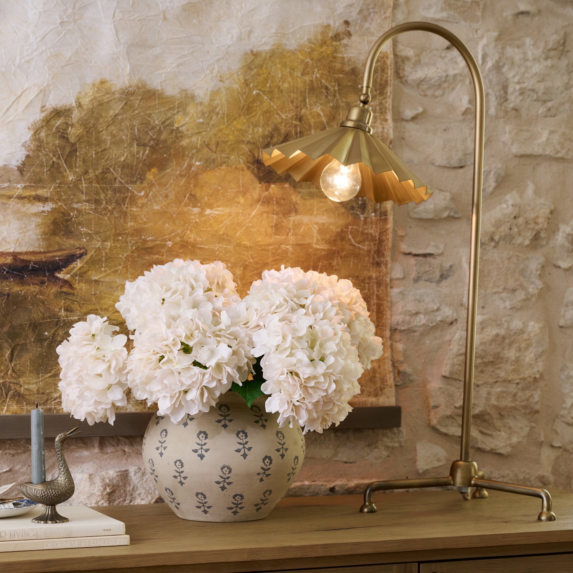 Oversized Brass Pleat Task Lamp on top of sideboard next hydrangeas in vase