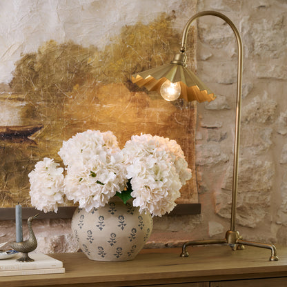 Oversized Brass Pleat Task Lamp on top of sideboard next hydrangeas in vase
