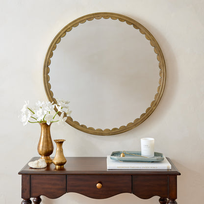 Julie Round Brass Scalloped Mirror in a room with brass vase with white daffodils and home fragrance