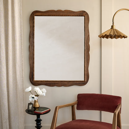 Caroline Carved Wood Mirror in a room with velvet chair and brass fluted floor lamp