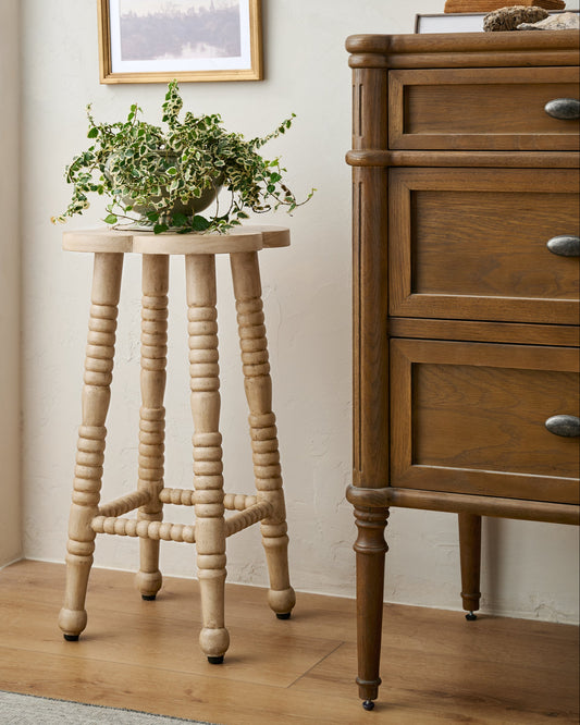 Jude Counter Stool in Light Wood with potted plant on top next to dresser