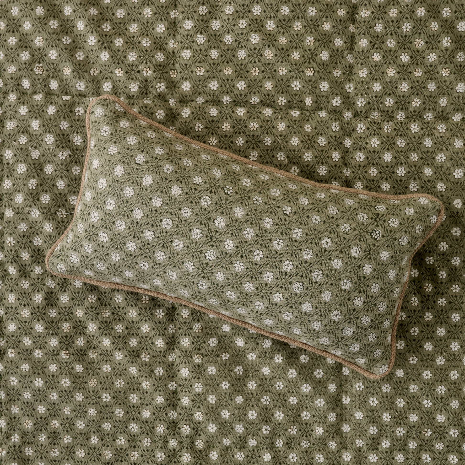 Thea Reversible Lumbar Pillow (small) on top of quilt bedding