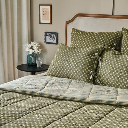 Thea Reversible Quilt on bed next to black end table