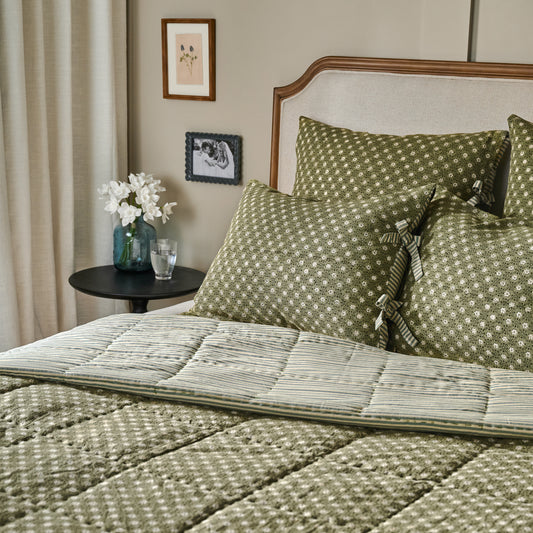 Thea Reversible Quilt on bed next to black end table