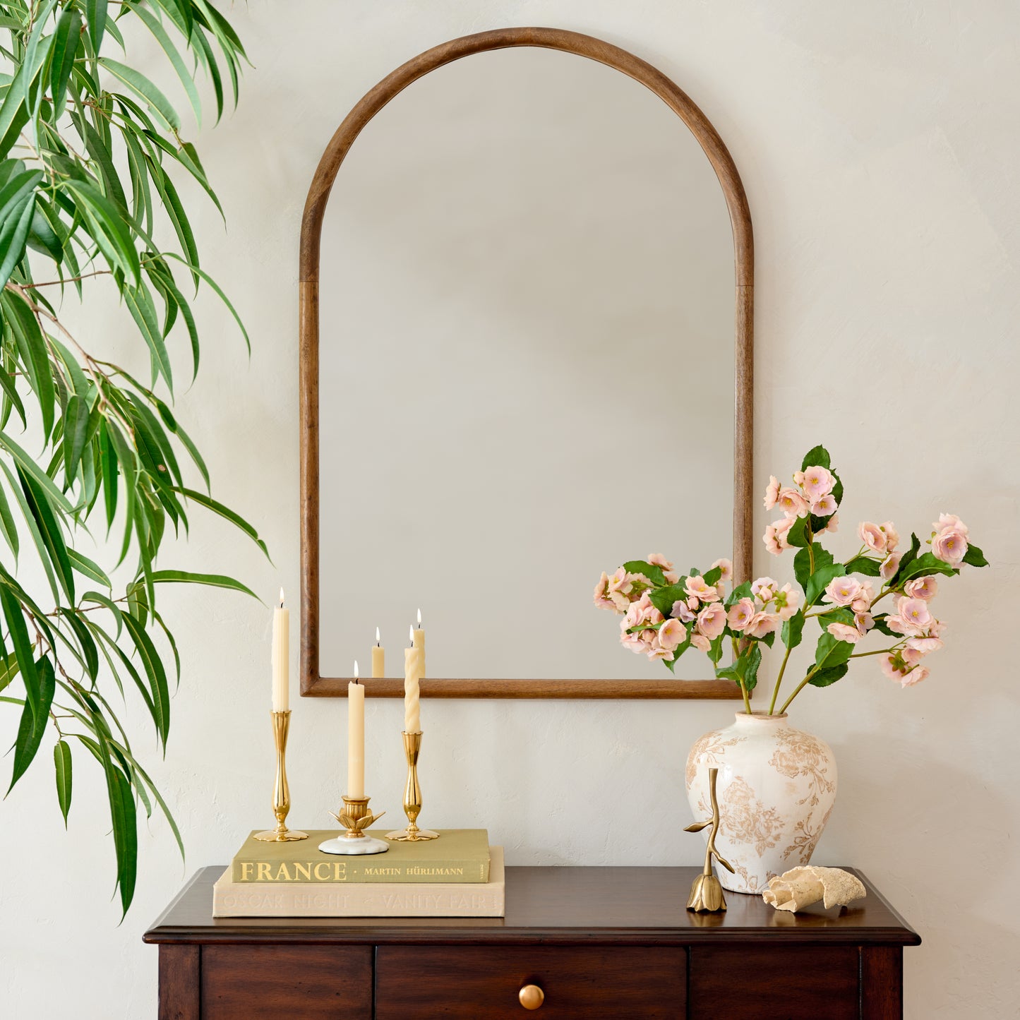 Archer Wood Framed Mantle Mirror on wall above console table with floral canister with blossom stems and taper candles