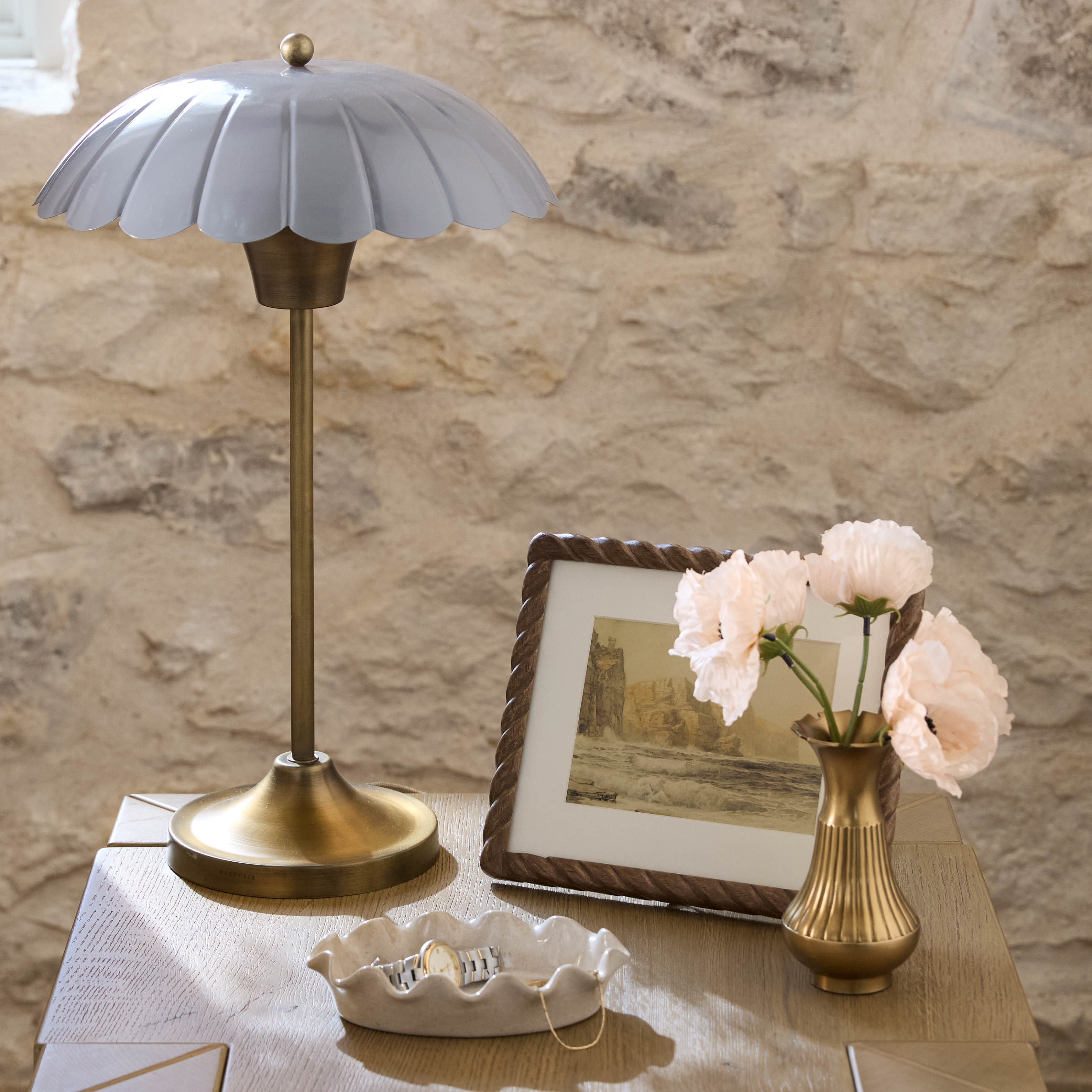 Decorative table lamp with a vase of flowers and a framed picture on a stone surface.