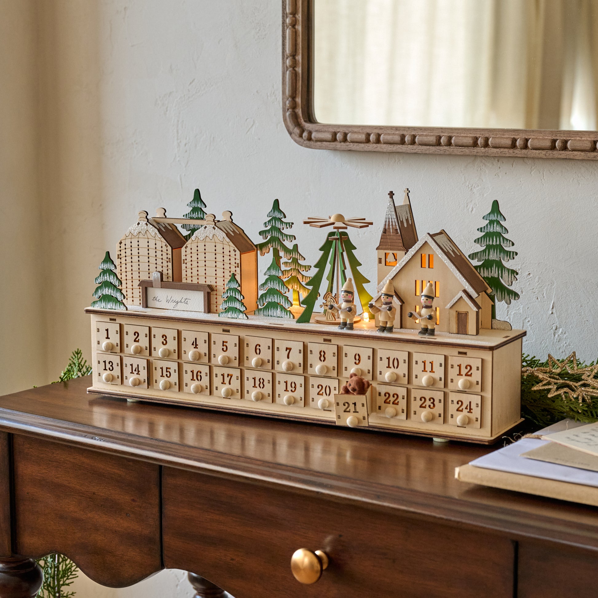 Wooden advent calendar with festive village scene on a wooden surface.