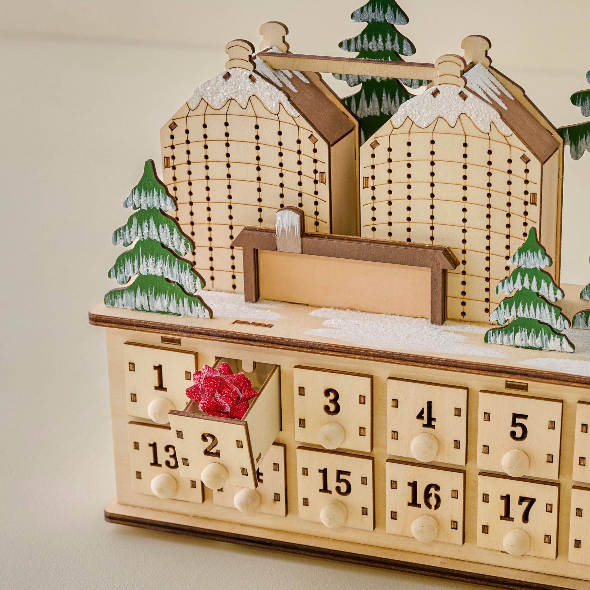 Wooden advent calendar with houses and trees on a plain background