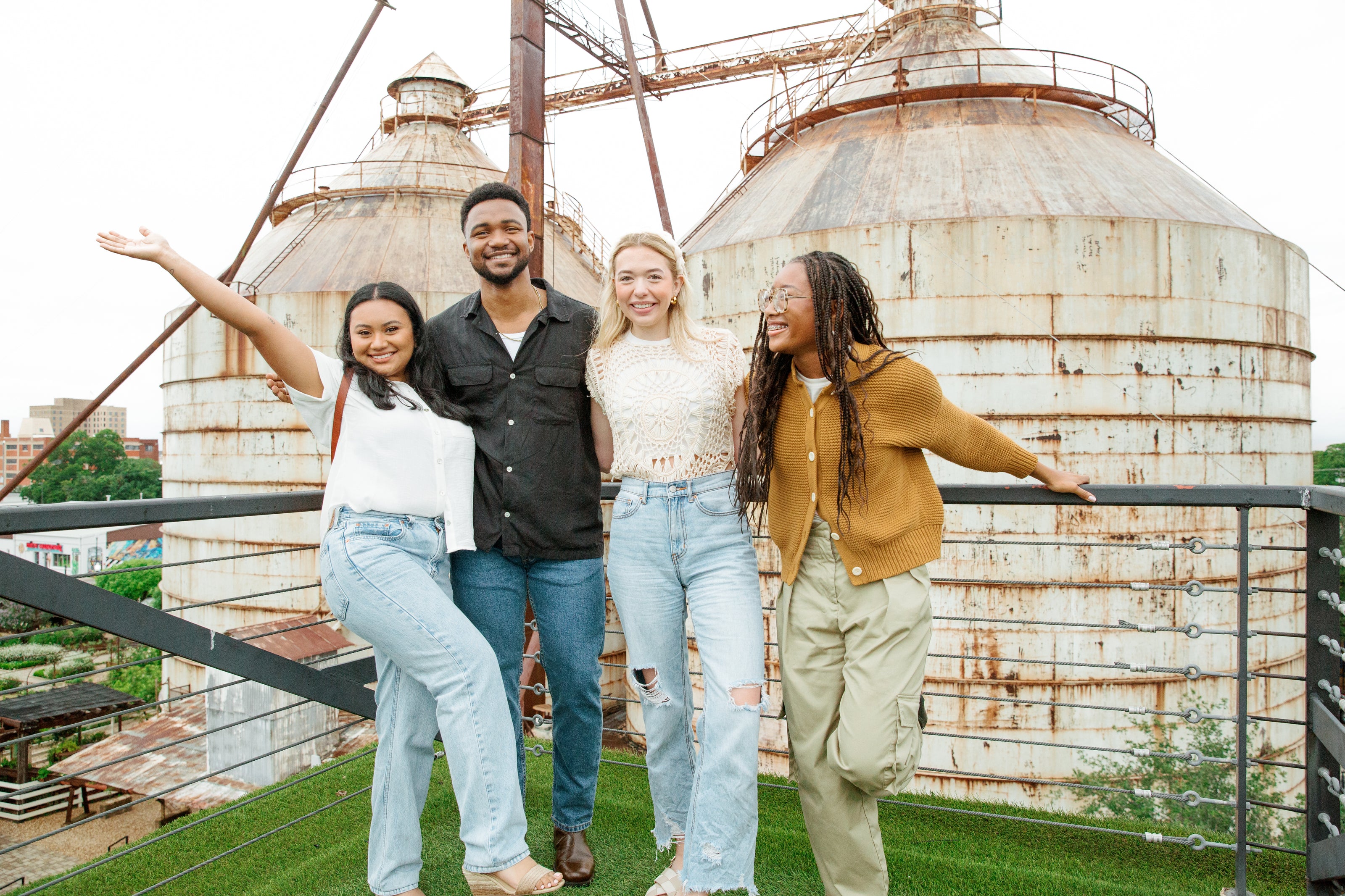 Four friends posing in front of a large industrial silo.