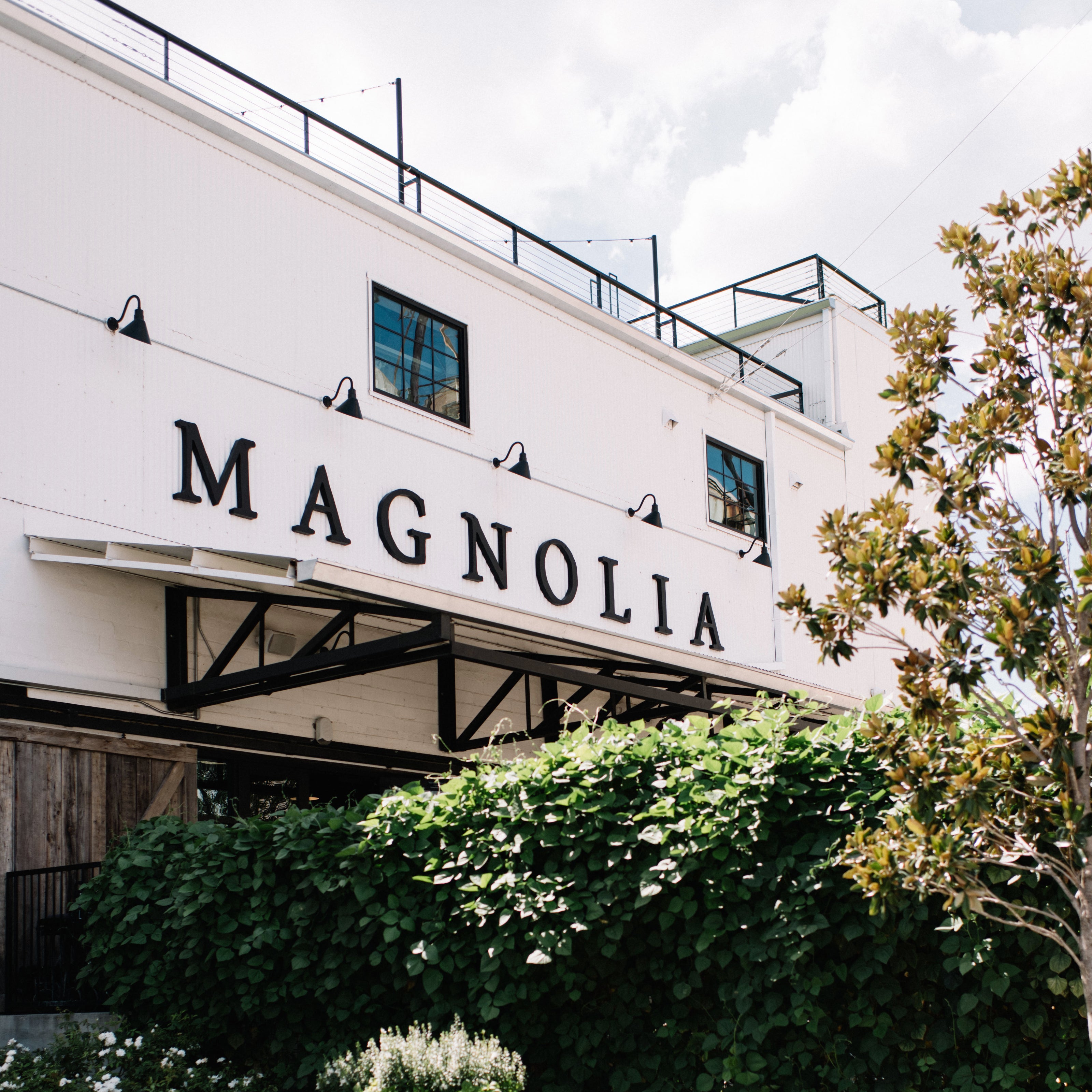 Building with 'Magnolia' sign above greenery