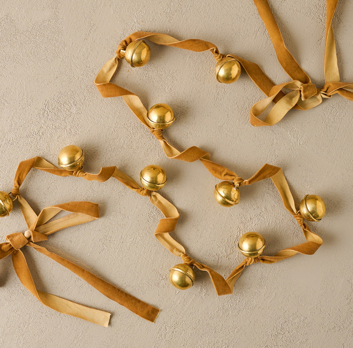 Gold bell garland with ribbons on a beige background