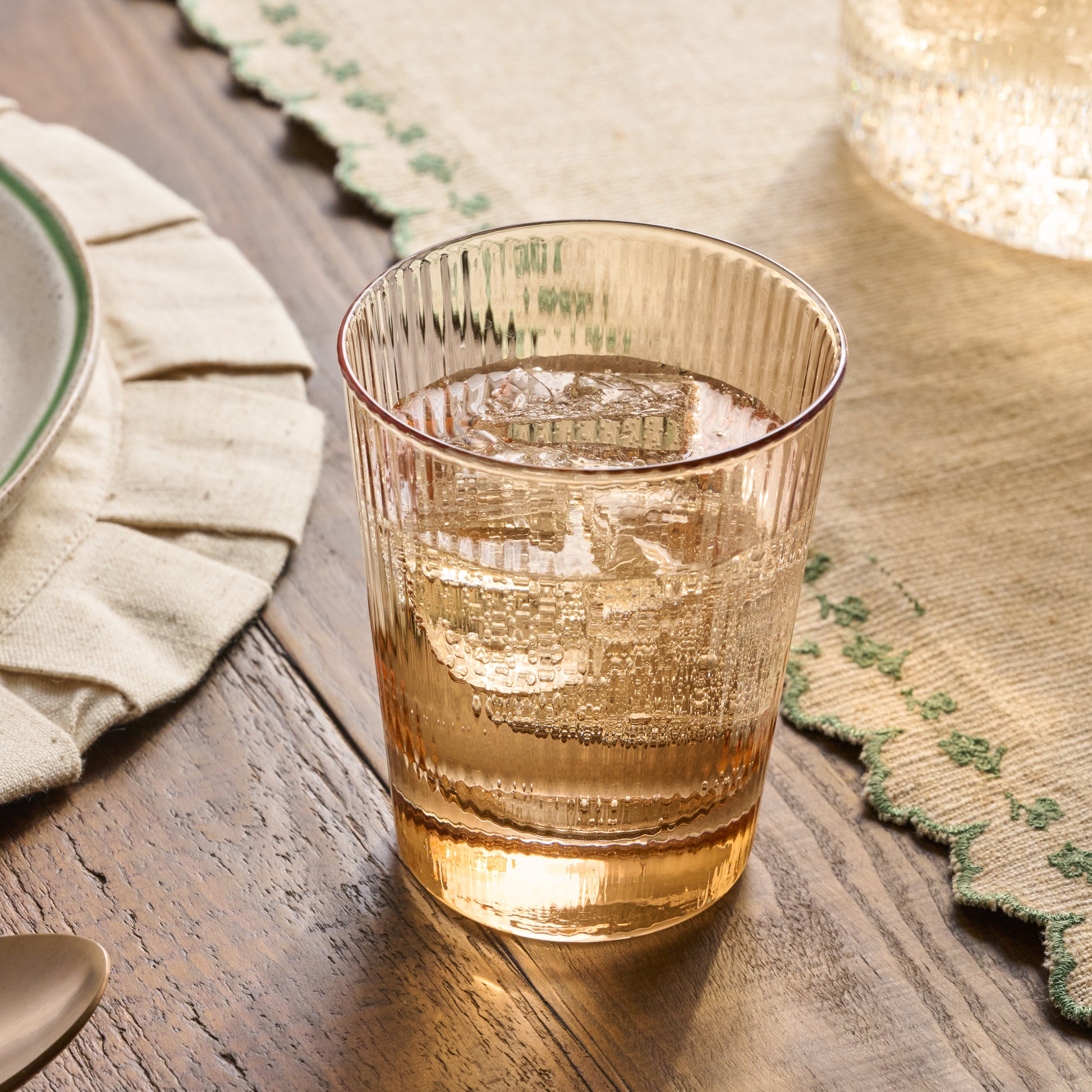 Peach Ribbed Glass Tumbler shown on table filled with water