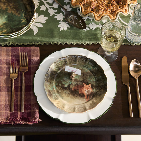 Dining table setting with a plate featuring a fox design, cutlery, and glasses.