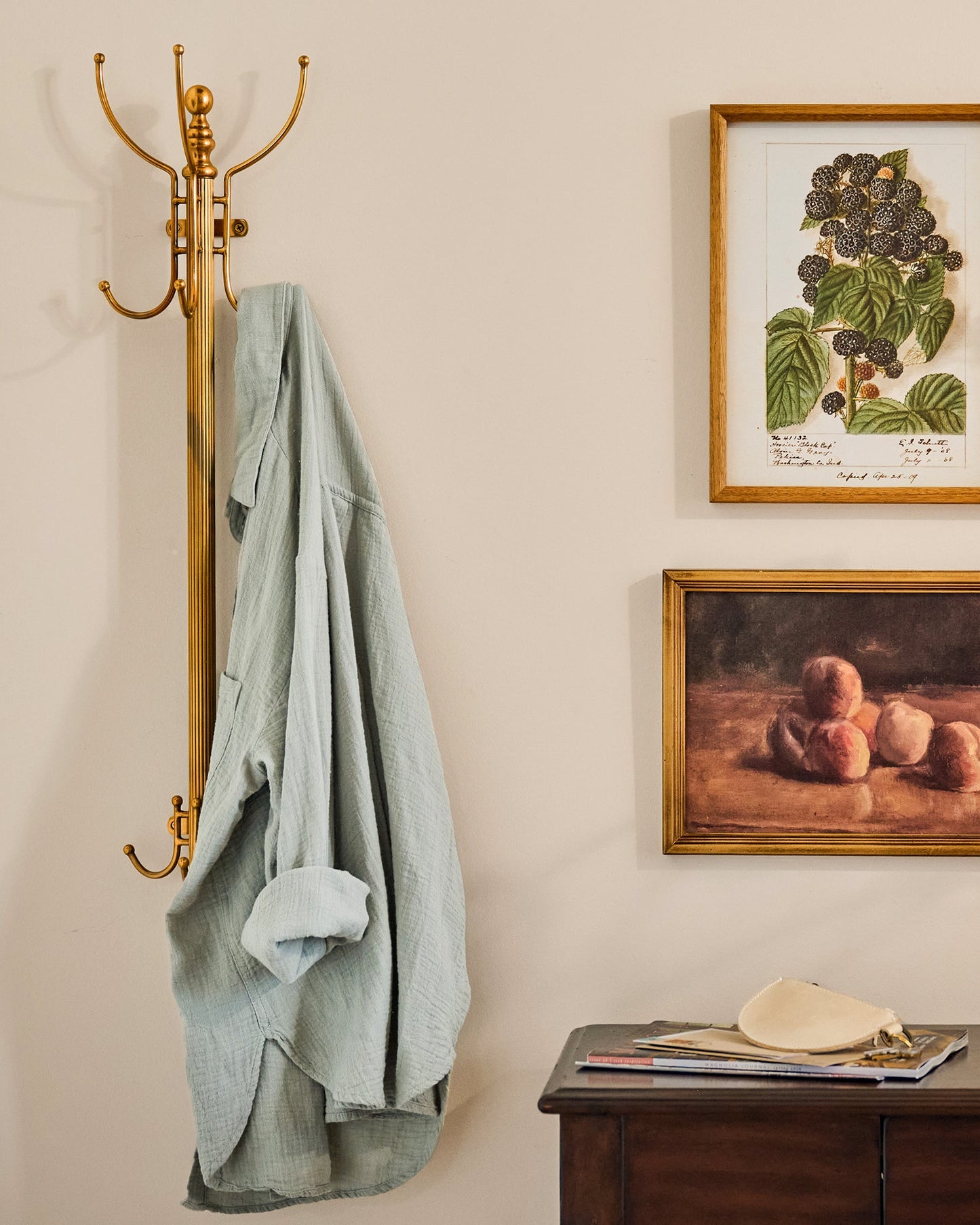 Antique Inspired Brass Coat Rack shown with coat and wall art