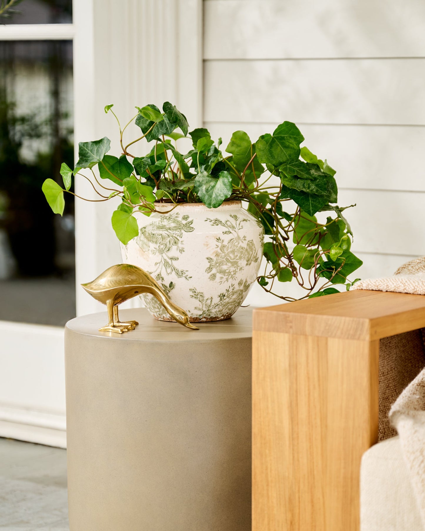 Antique Inspired Solid Brass Duck grazing outside on side table with vase