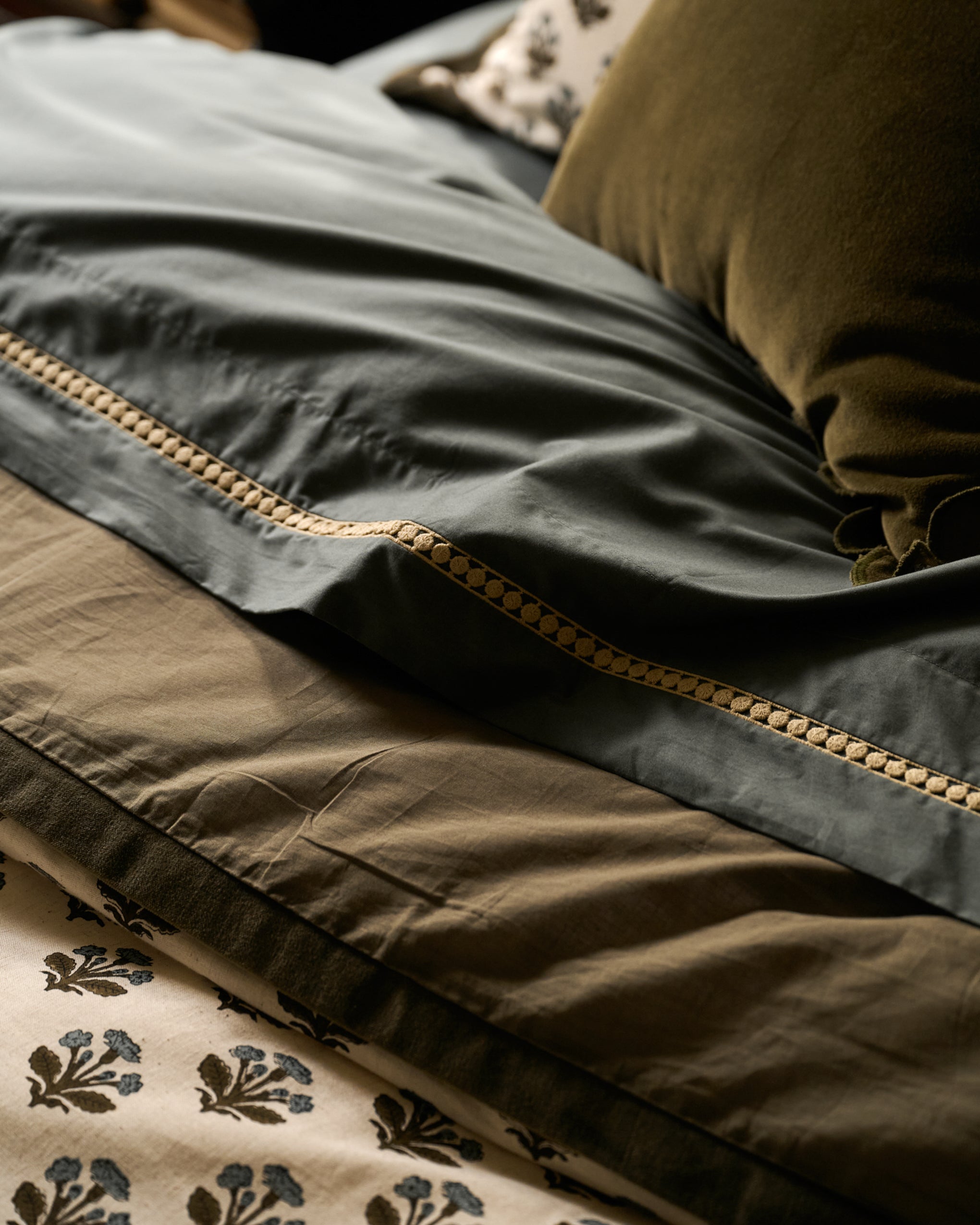 Stack of folded fabric pieces in green, brown, and beige with floral pattern.