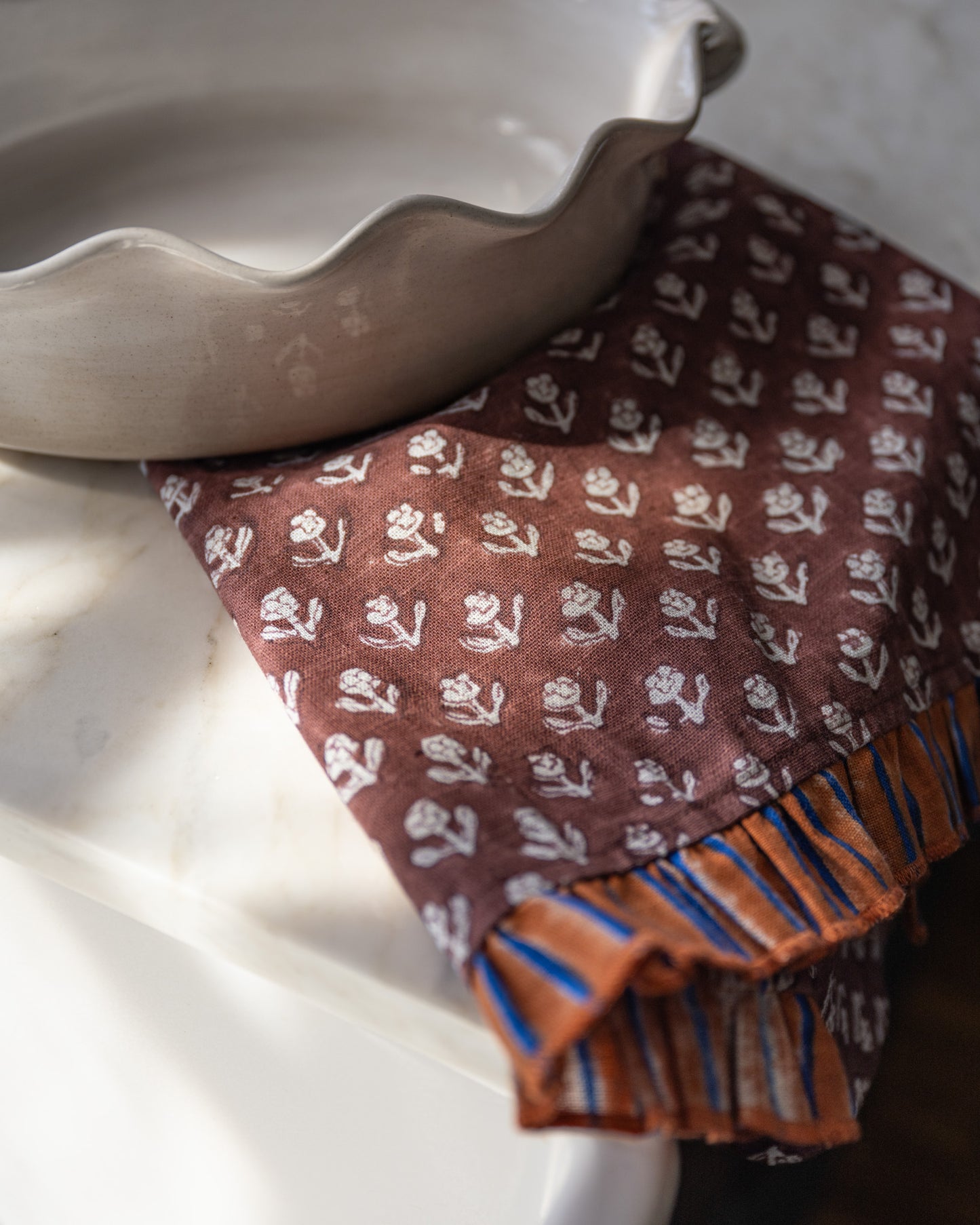 Chocolate Cosmos Block Printed Tea Towel close up underneath scalloped dish