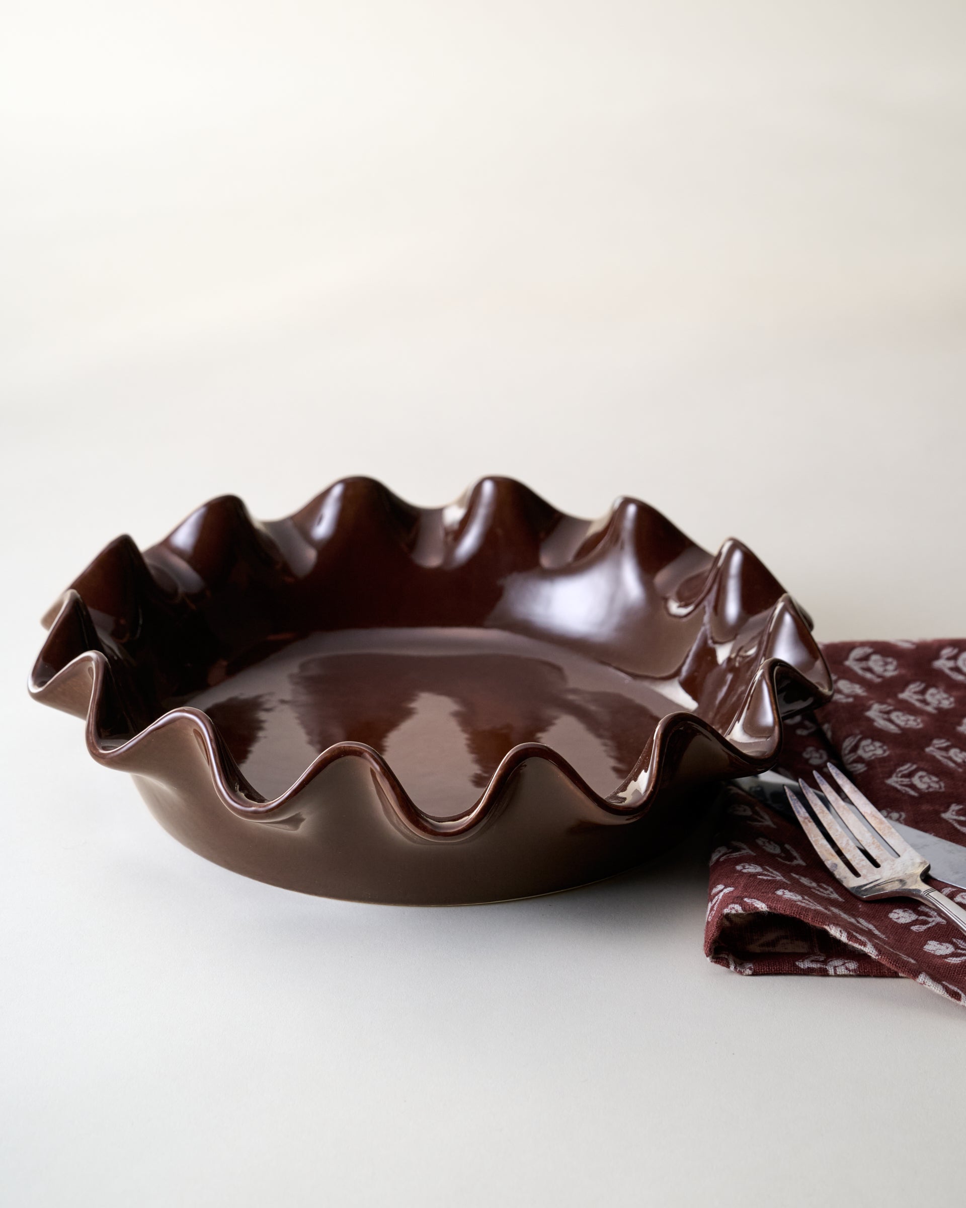 Chocolate Scalloped Pie Dish with tea towel and flatware