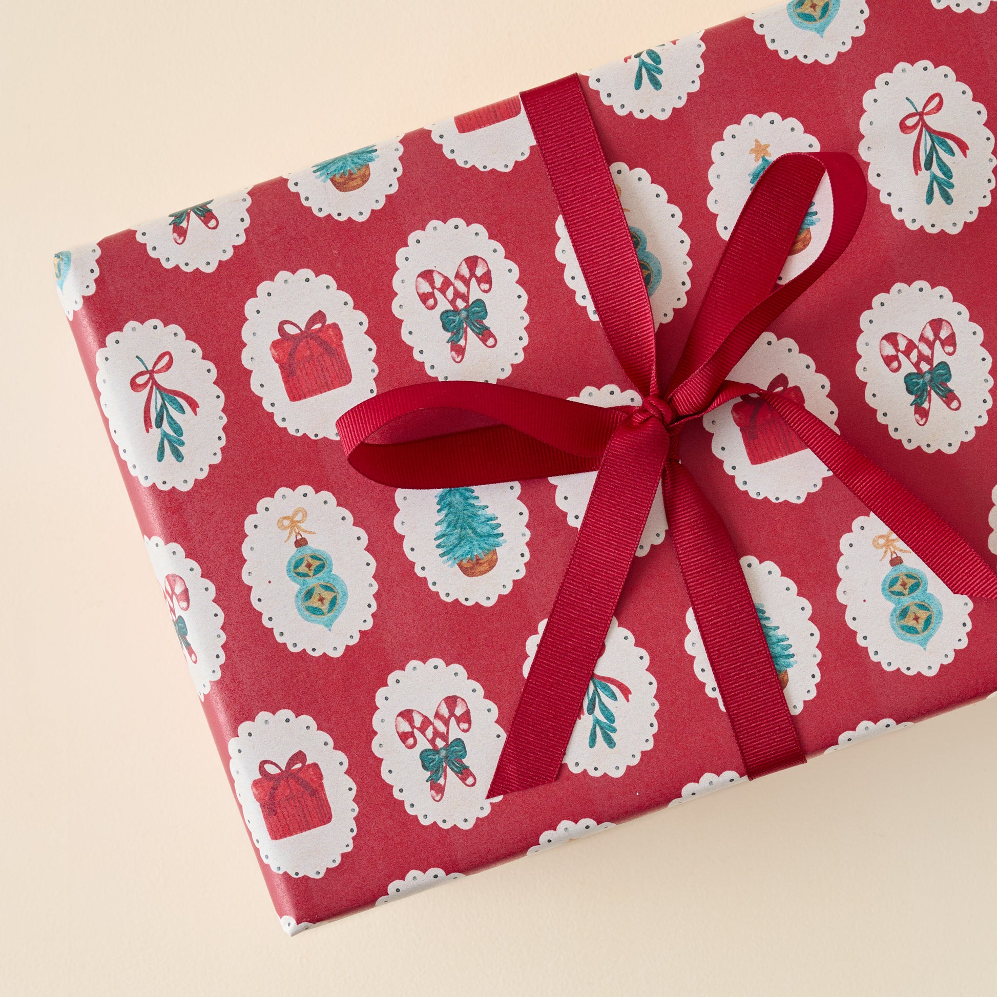 Red Cameo Christmas Wrapping Paper Roll shown on gift with red ribbon