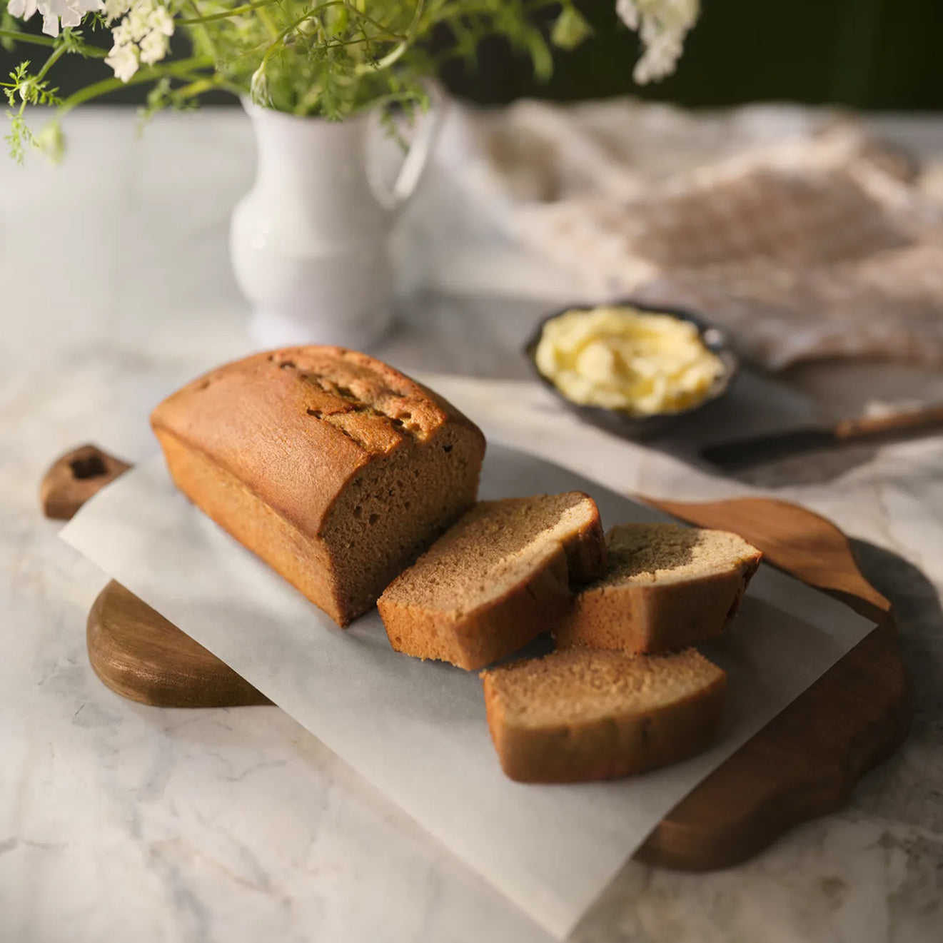 A sliced loaf of Magnolia Table After School Banana Bread on a cutting board.