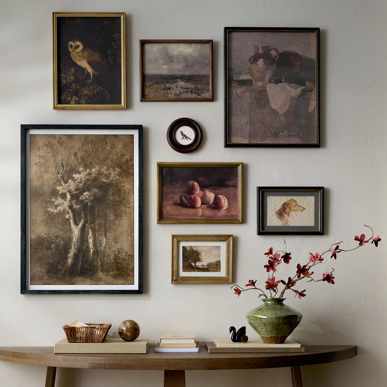 Wall with framed art pieces and a vase with flowers on a wooden table.