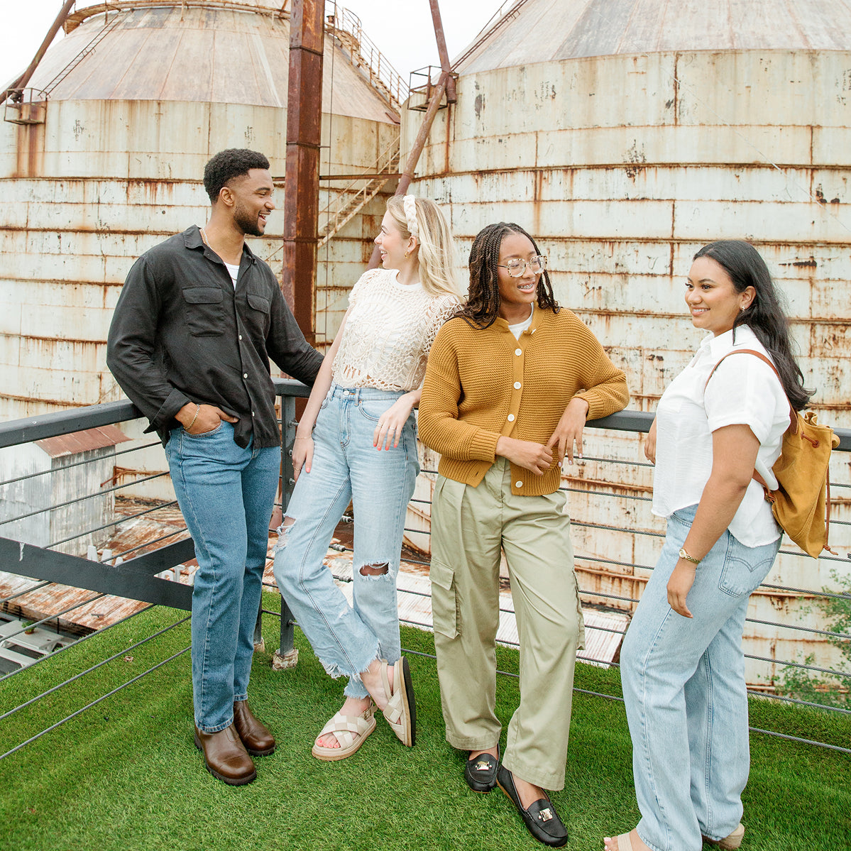 Four friends standing on a rooftop with the Silos in the background