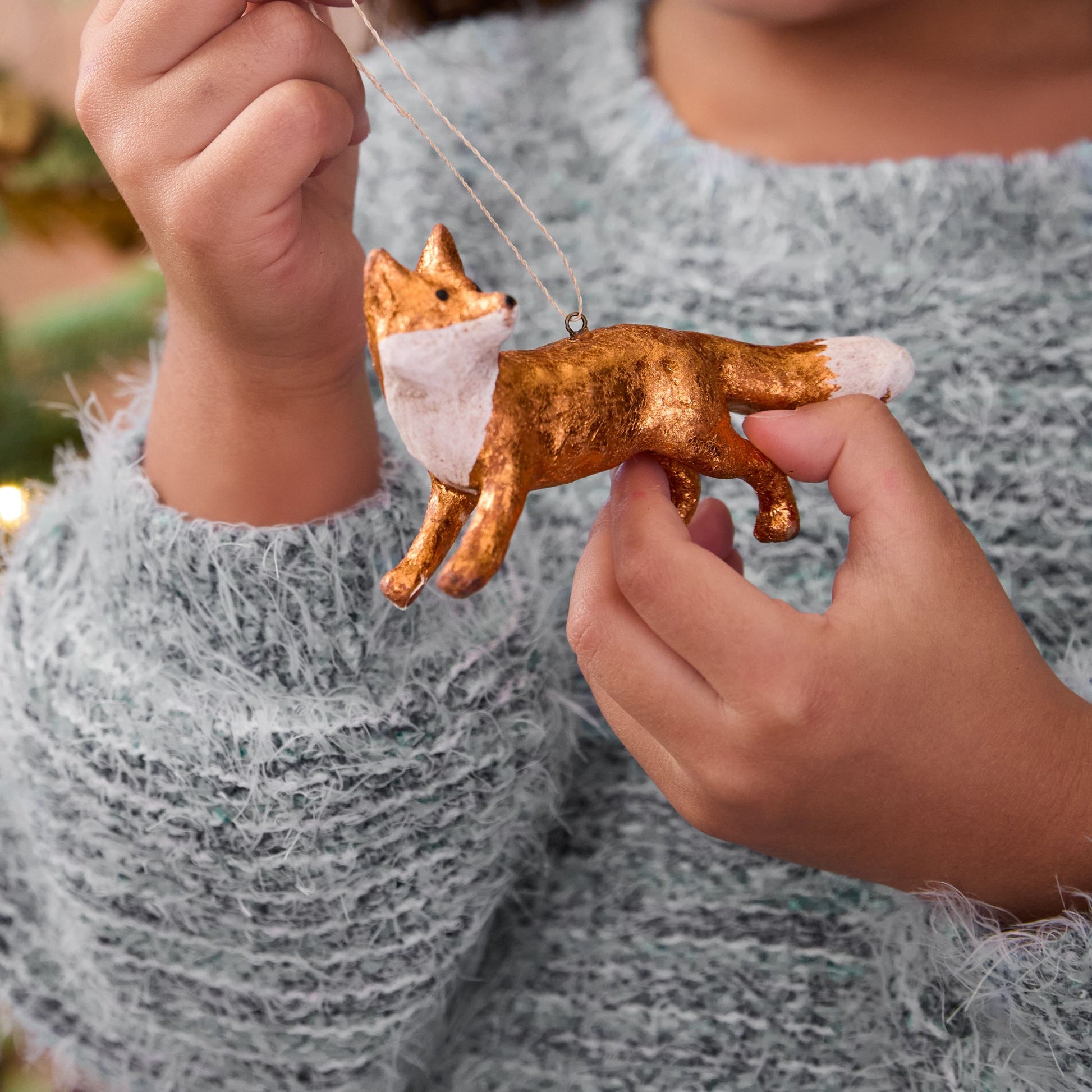 Person holding a small gold fox ornament