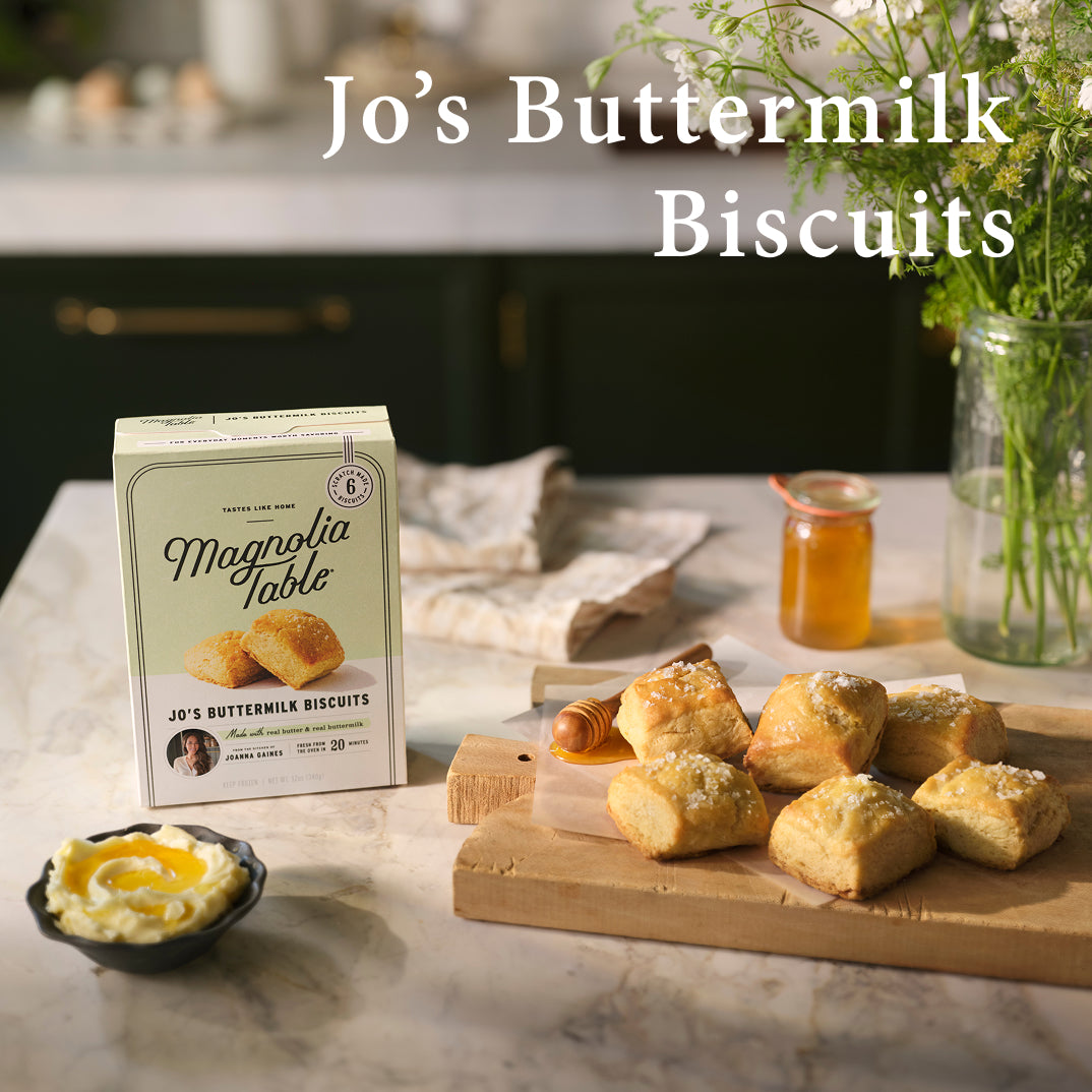 Box of Magnolia Table Jo's Buttermilk Biscuits on a kitchen counter with jo's buttermilk biscuits and honey.