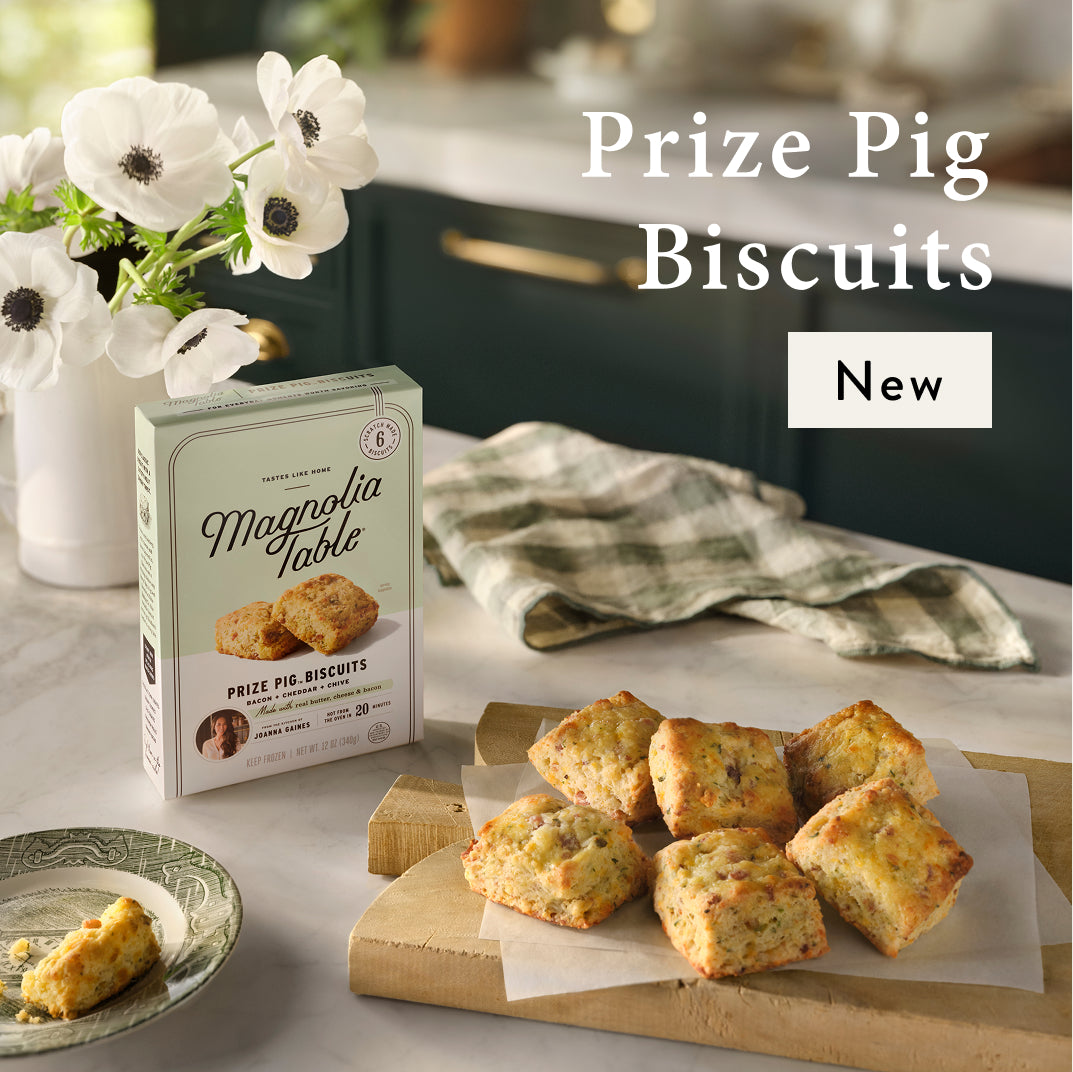 Magnolia Table Prize Pig Biscuits packaging with prize pig biscuits on a cutting board in a kitchen setting.