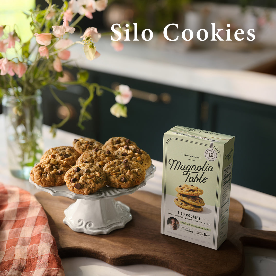 Magnolia Table Silo cookies on a cake stand with a box of Magnolia Table Silo Cookies in a kitchen setting.
