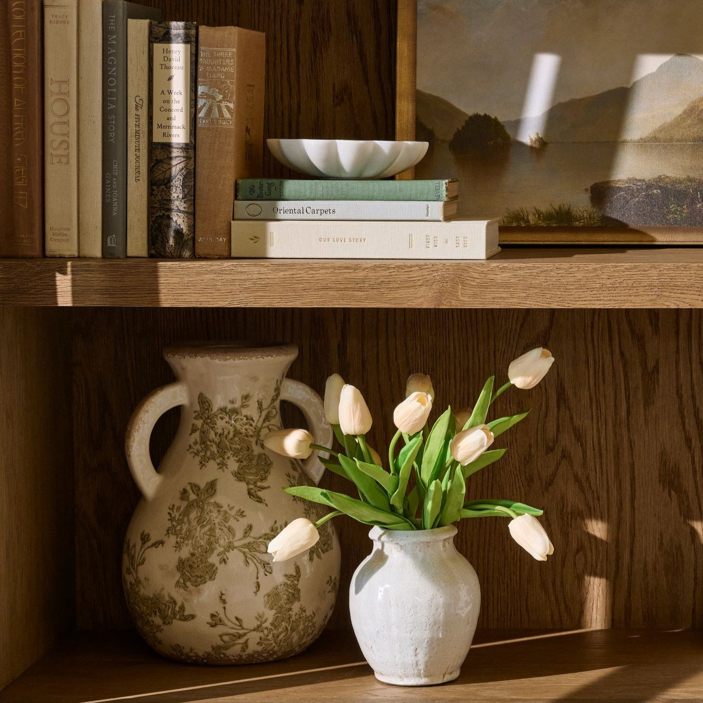 green and white distressed vase on shelf next to smaller white vase with tulips