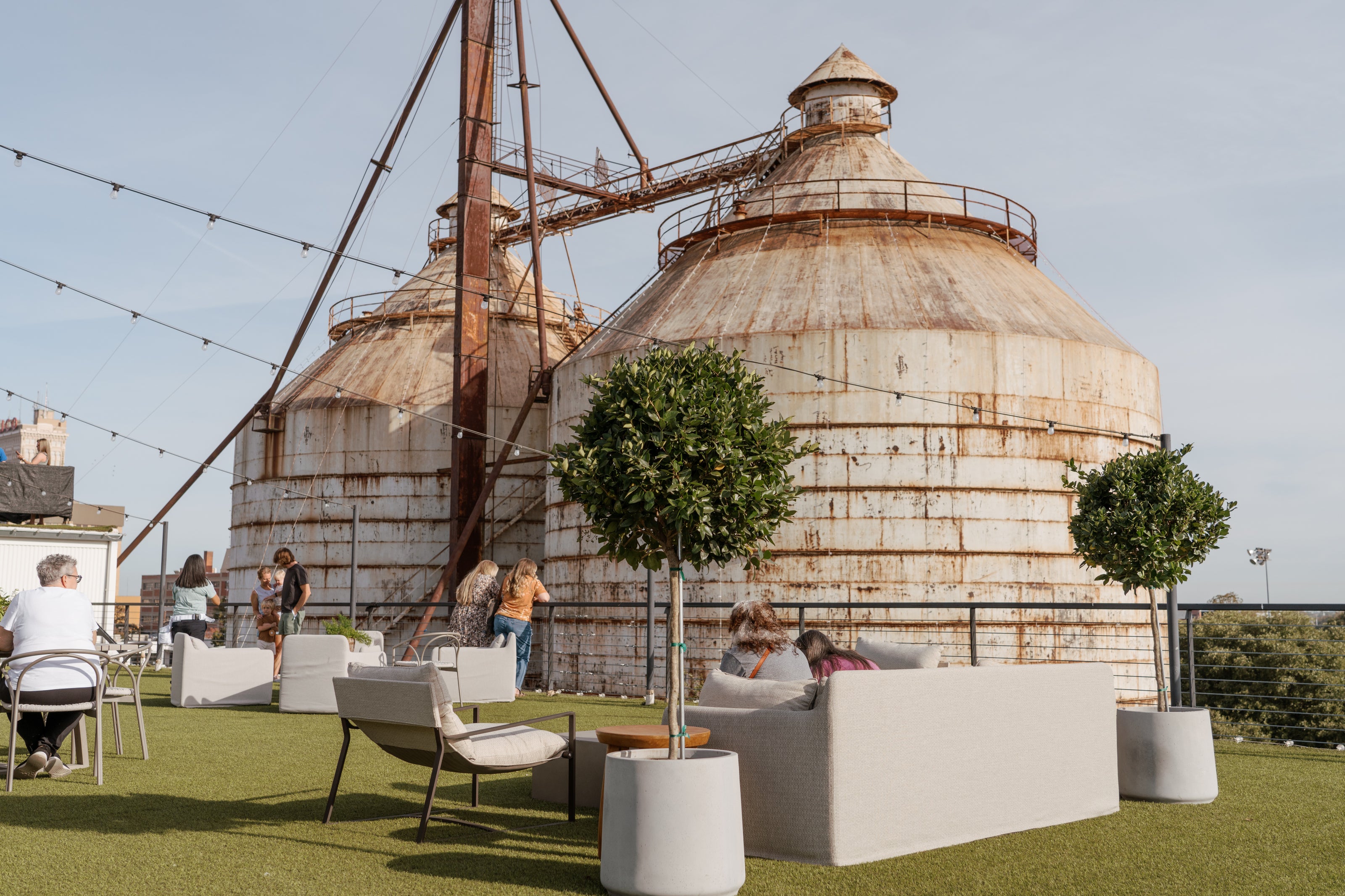People sitting on a rooftop with the Magnolia Silos in the background
