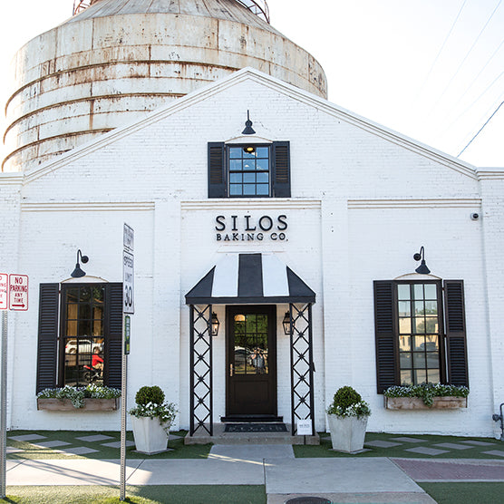 White building with a view of the Silos, featuring the 'SILOS Baking Co.' sign.