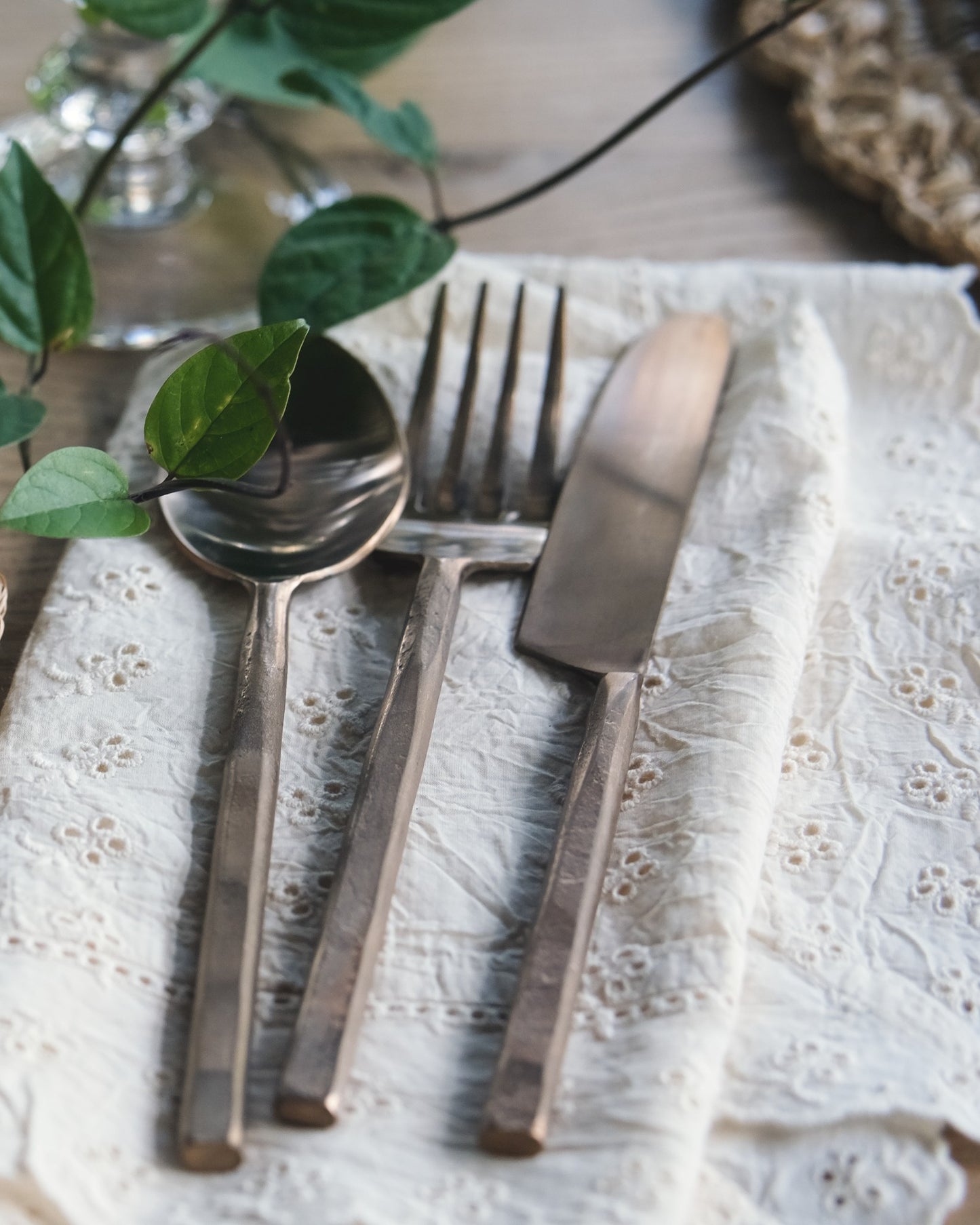 Vintage silverware set on a textured white cloth with green leaves.