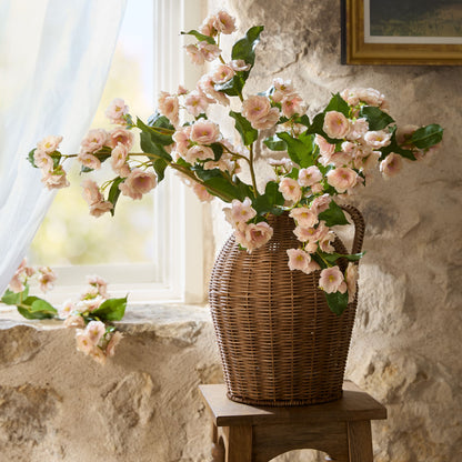 peach blossom stems arranged in a rattan woven vase