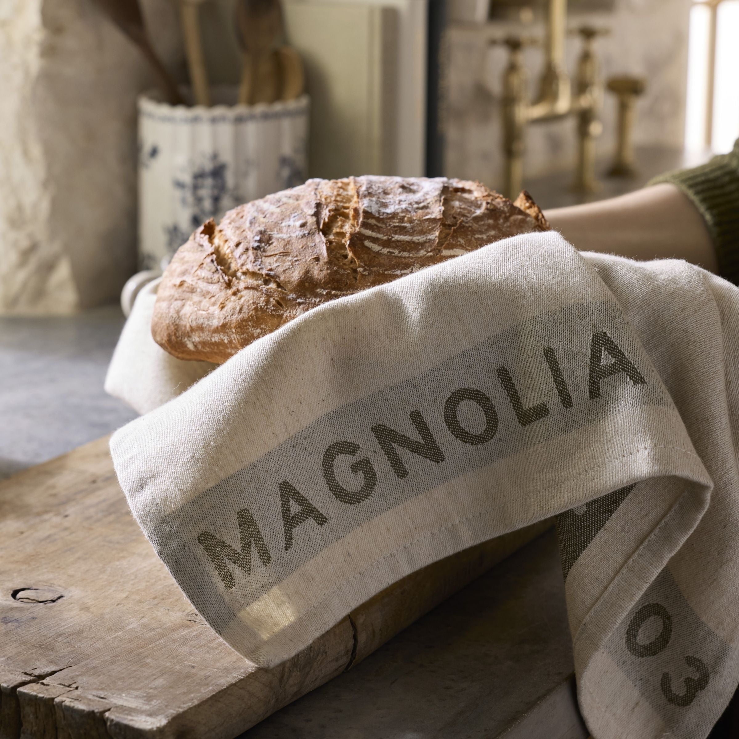 Loaf of bread on a Magnolia branded towel in a kitchen setting