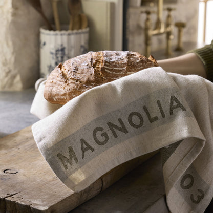 Loaf of bread on a Magnolia branded towel in a kitchen setting