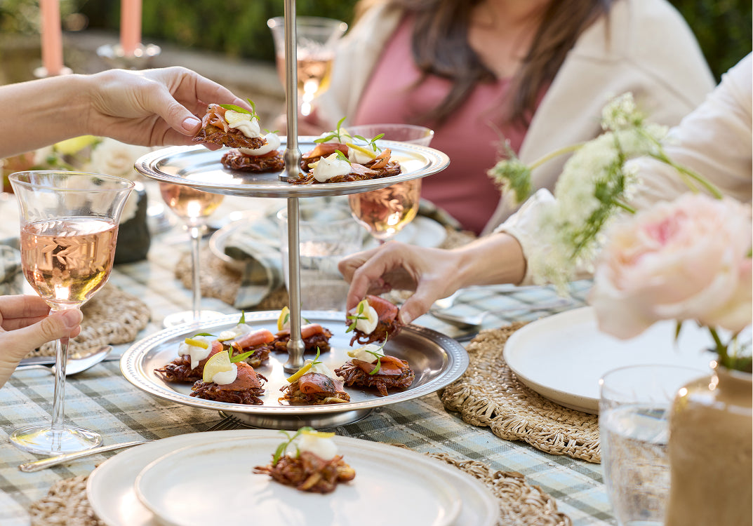 Two tiered tray with appetizers on each tray sitting on a dining table.