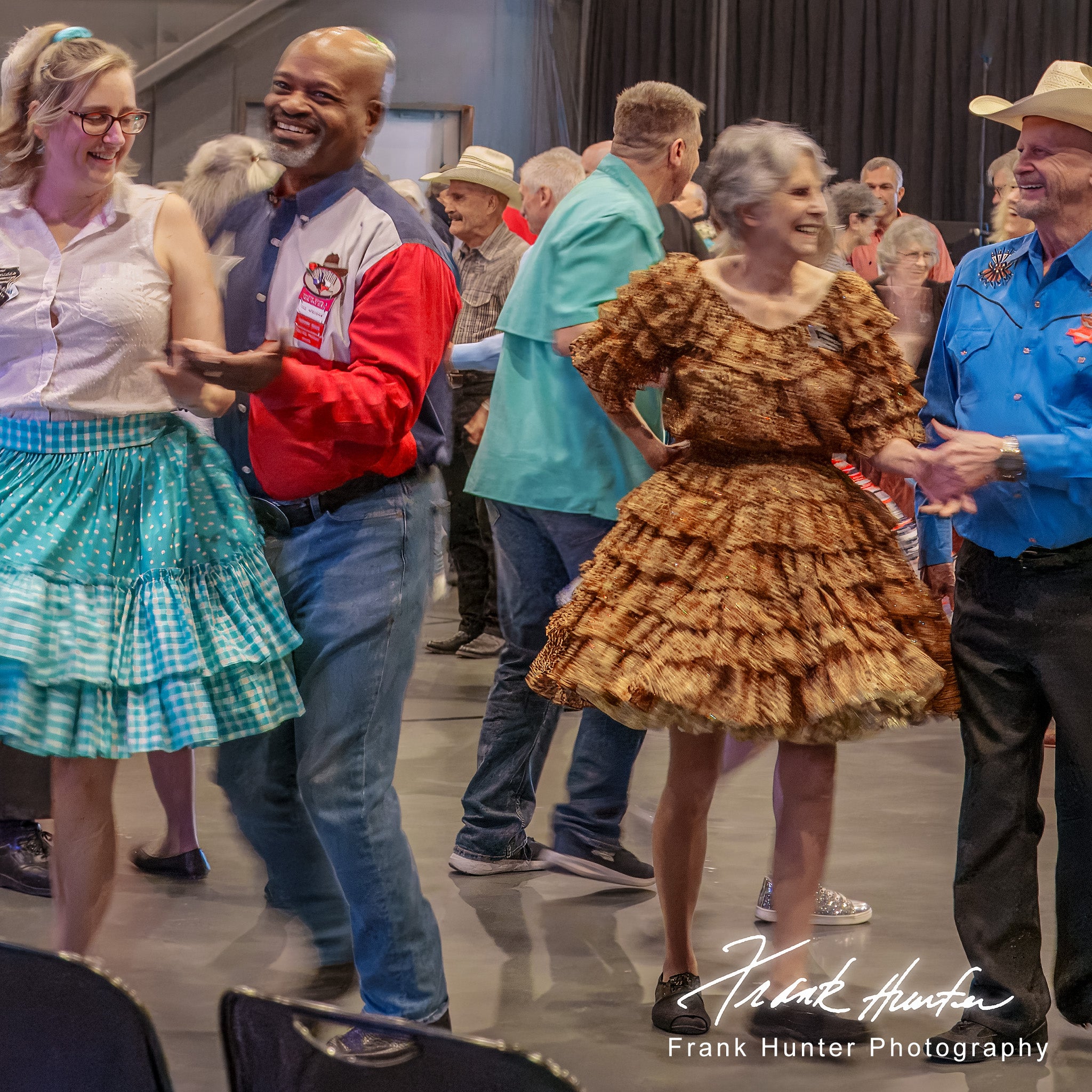 Group of people dancing in a social setting with a focus on a couple in the foreground.