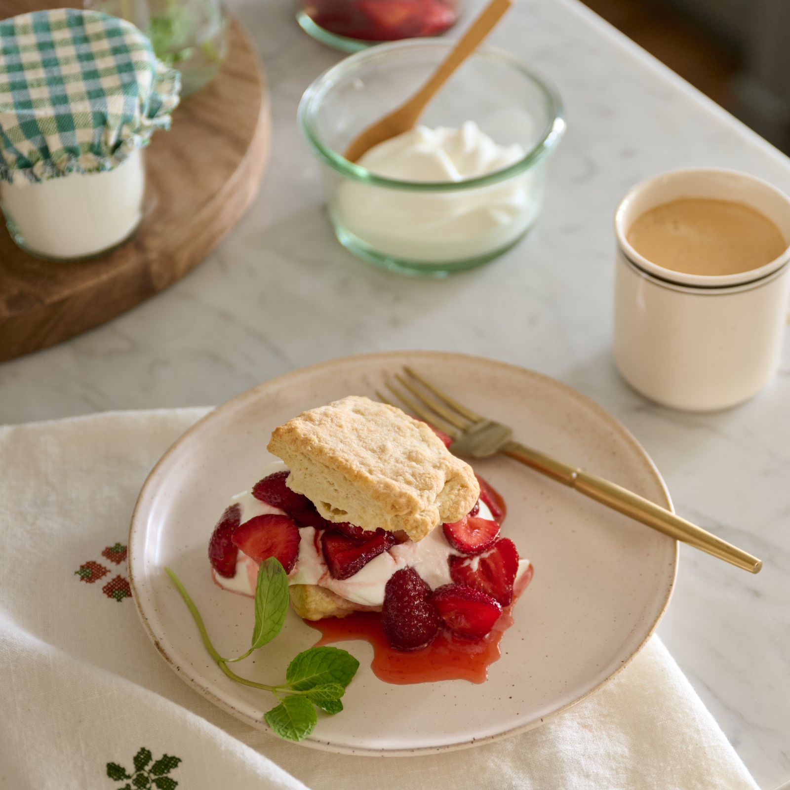 Strawberry shortcake with whipped cream on a plate, served on a table with a patterned tablecloth.