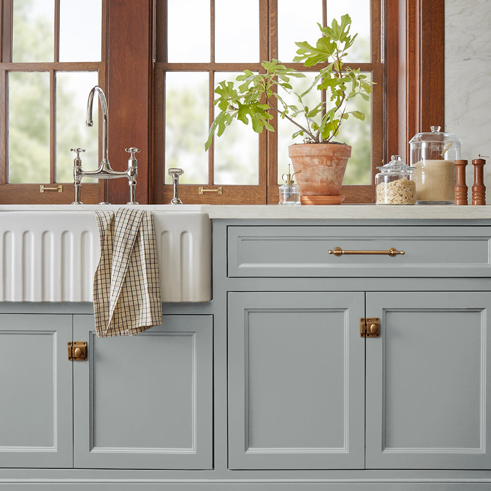 neutral grey with a tinge of blue paint color named tranquil waters shown painted on kitchen cabinets
