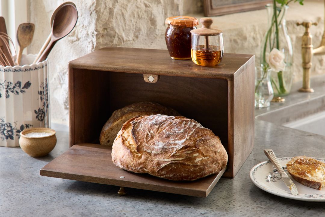 Wooden bread box with loaves of sourdough bread on a kitchen counter.